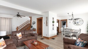 A spacious living room with a brown leather sofa, a wooden coffee table, and a dining area with a white table and chairs. - -RARE- In-Village rental! 4-Bedrooms w HOT TUB & AC
 (Ellicottville)