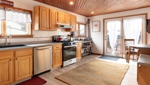 A kitchen with wooden cabinets, a stove, and a dishwasher. - -RARE- In-Village rental! 4-Bedrooms w HOT TUB & AC
 (Ellicottville)