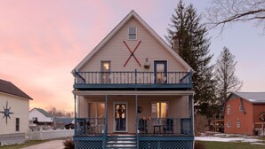 A two-story house with a porch and a visible staircase leading to the entrance. - -RARE- In-Village rental! 4-Bedrooms w HOT TUB & AC
 (Ellicottville)