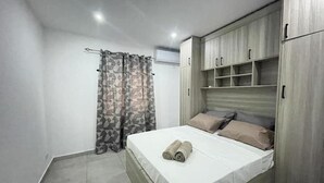 A bedroom with a bed, curtains, and built-in wardrobe.