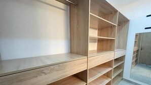 A modern, empty walk-in closet with wooden shelves and a mirrored door.