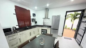 A compact kitchen with a dining area, a built-in oven, and a refrigerator.