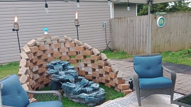 A backyard with a fire pit, two blue chairs, and a stone wall. - Camp Lilybug-Calm Oasis Pet Friendly! (Terre Haute)