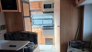A compact RV interior with a kitchenette, a dining area, and a sleeping area. - Camp Lilybug-Calm Oasis Pet Friendly! (Terre Haute)
