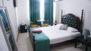 Una habitación de hotel con cama, escritorio, silla, lámpara y espejo.