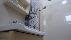 Un baño con ducha, lavamanos y un perchero para toallas.