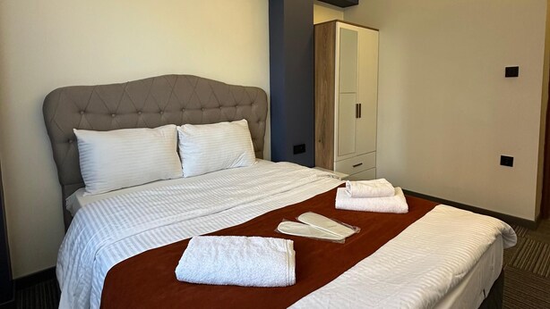 Habitación de hotel con una cama grande, un armario y aire acondicionado instalado en el techo.