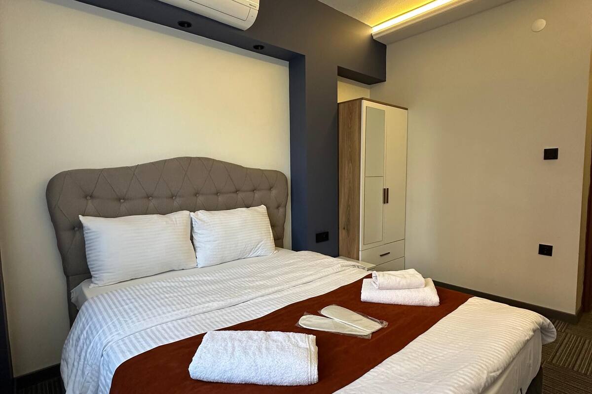 Quarto de hotel com uma cama grande, um guarda-roupa e ar condicionado no teto.