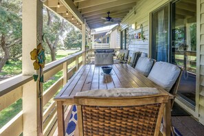 Enjoy outdoor dining or relaxation on this covered porch with a table, chair, and comfortable cushion.