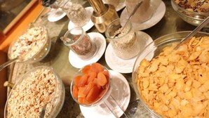Ein Buffet mit verschiedenen Speisen, darunter Granola, Trockenfrüchte und Müsli.