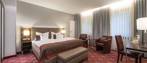 Een hotelkamer met een groot bed, een bureau, een stoel, een kleine tafel en een bank.