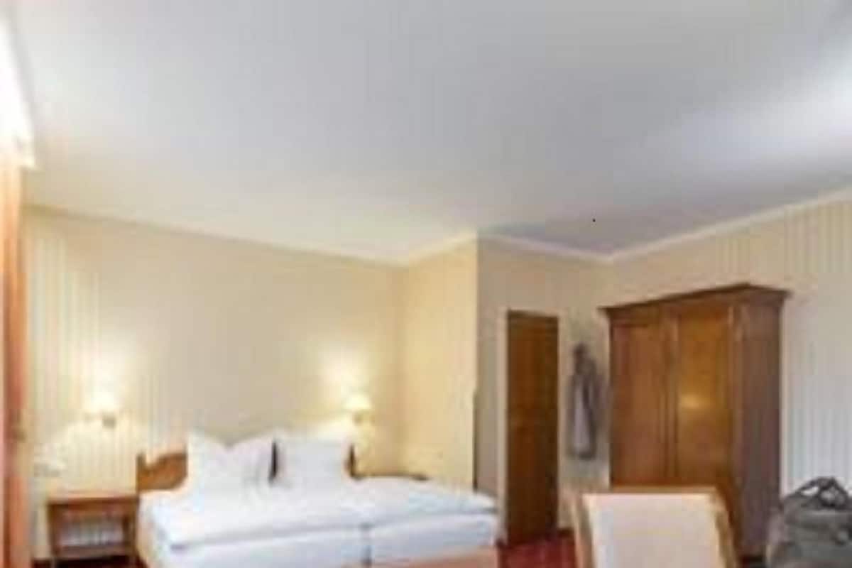 A hotel room with a bed, two bedside tables, a desk, a chair, and a wardrobe.