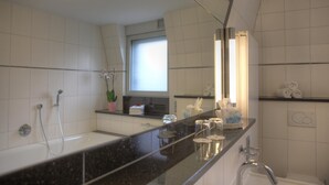 Ein modernes Badezimmer mit großem Spiegel, Dusche, Waschbecken und Fenster.