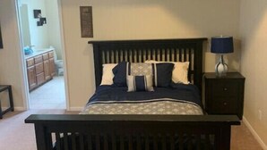 Un dormitorio con una cama de madera oscura, una mesita de noche con una lámpara y un ventilador de techo.