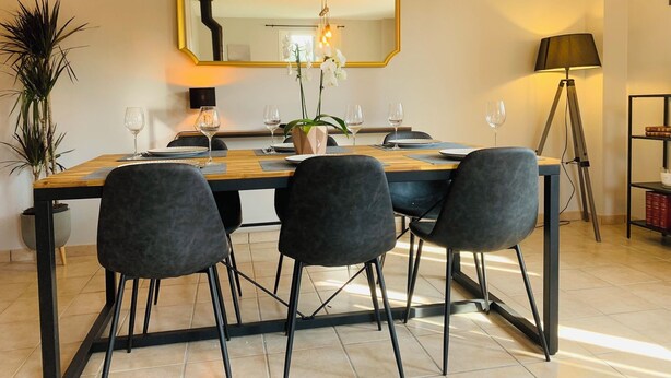 A dining area with a wooden table, four chairs, a large mirror, and a floor lamp.