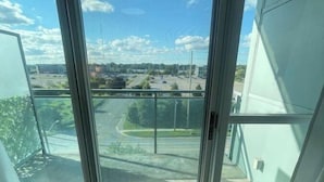 A room with a large sliding glass door leading to an outdoor area with a view of a road and buildings. - Lovely 1 bedroom unit with balcony. Sleeps 1-4 (Whitby)