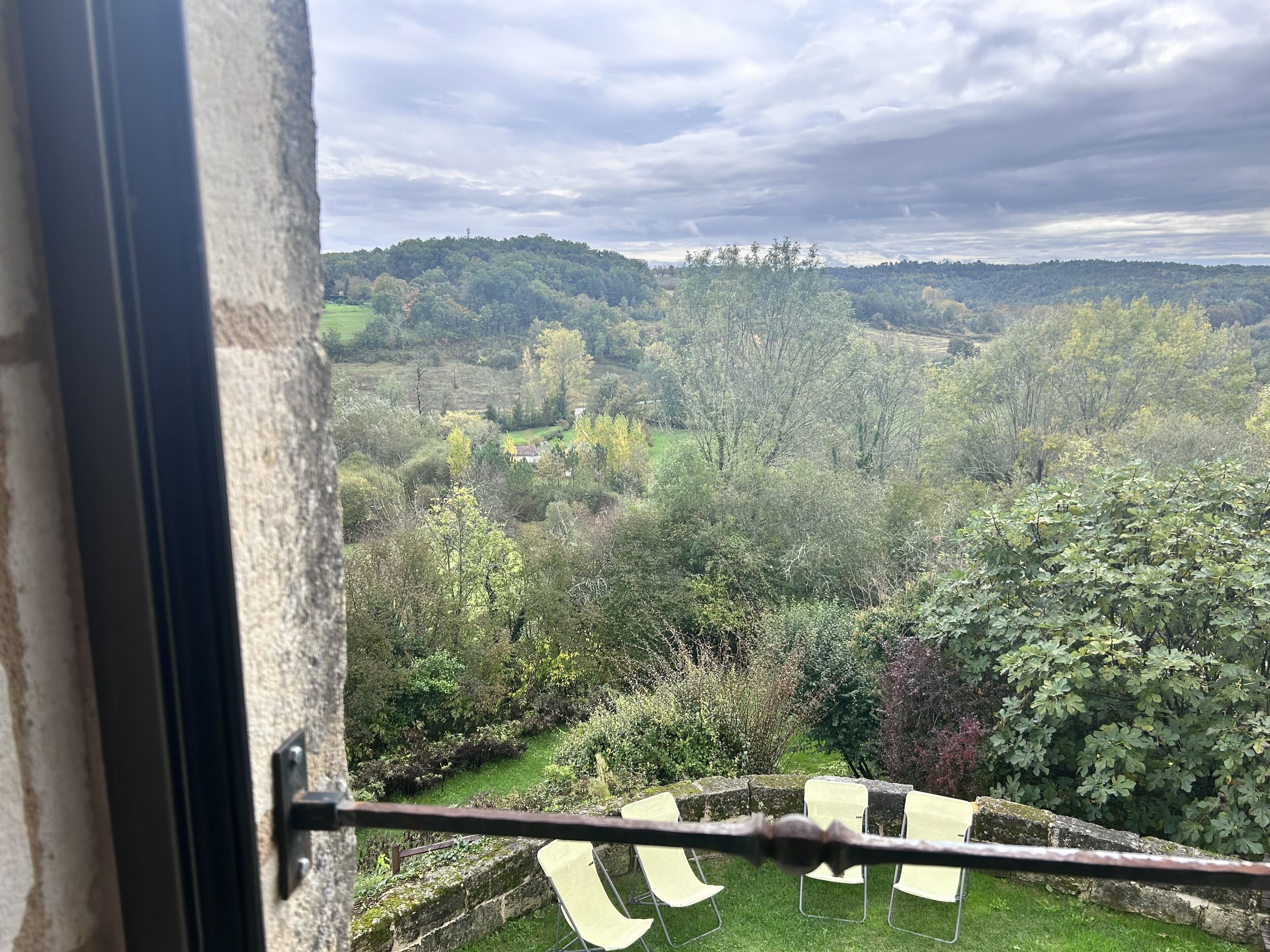 Vista da janela com jardim e área de estar externa.