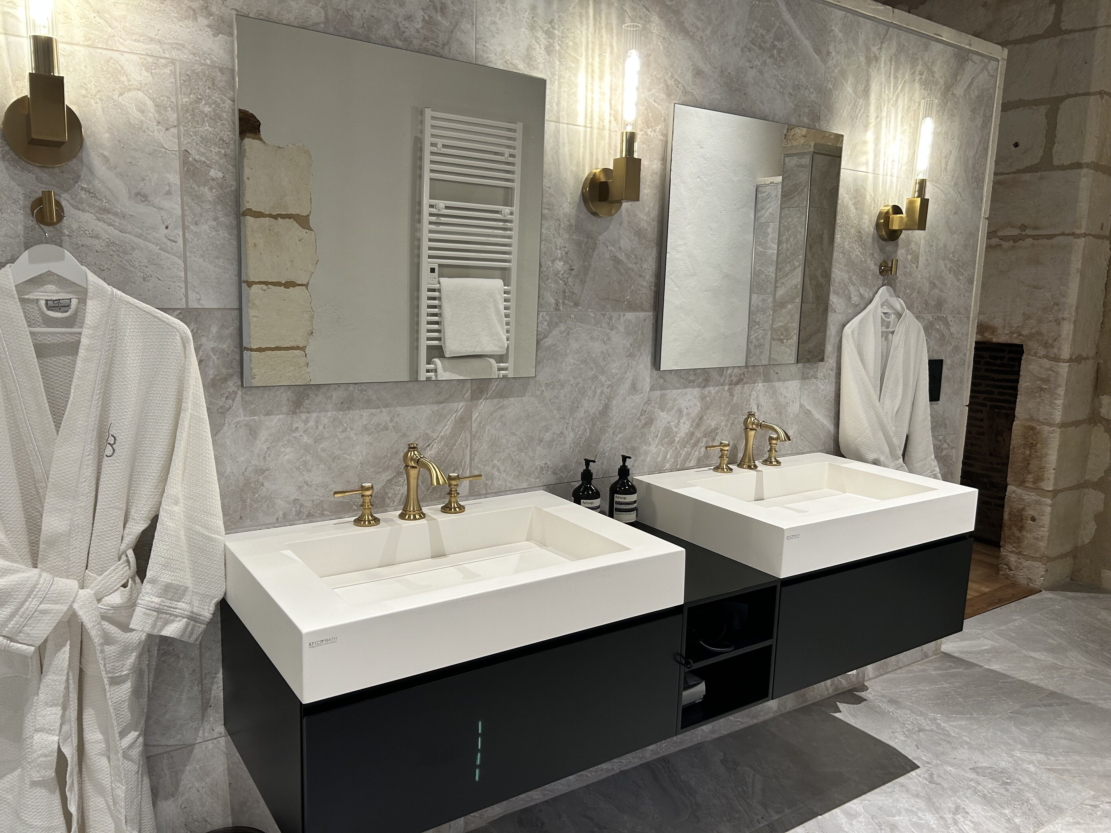 Un bagno moderno con due lavabi, uno specchio grande e un porta asciugamani.