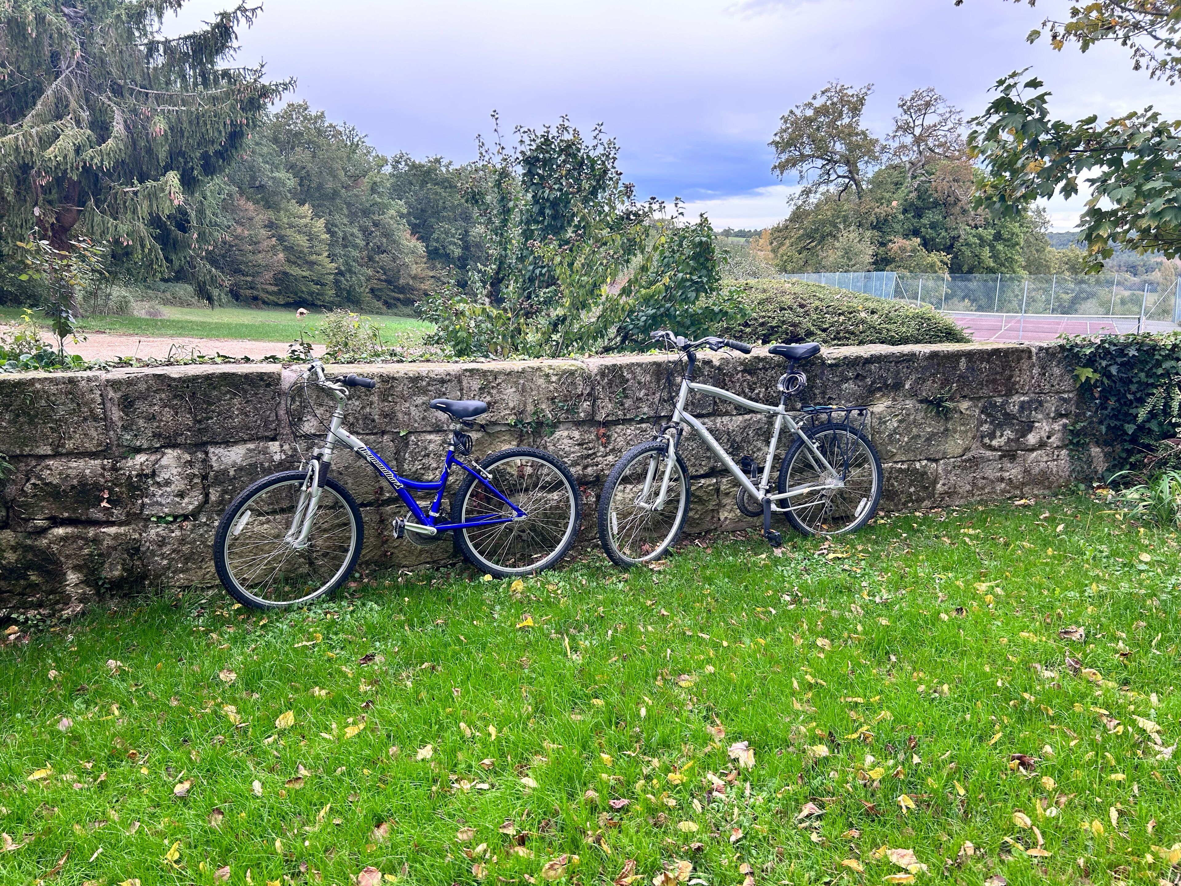 A stone wall with two bicycles parked against it.