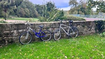 A stone wall with two bicycles parked against it.
