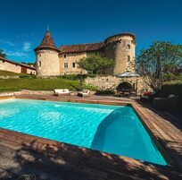 Un castillo con piscina, terraza de madera y zona de estar al aire libre.