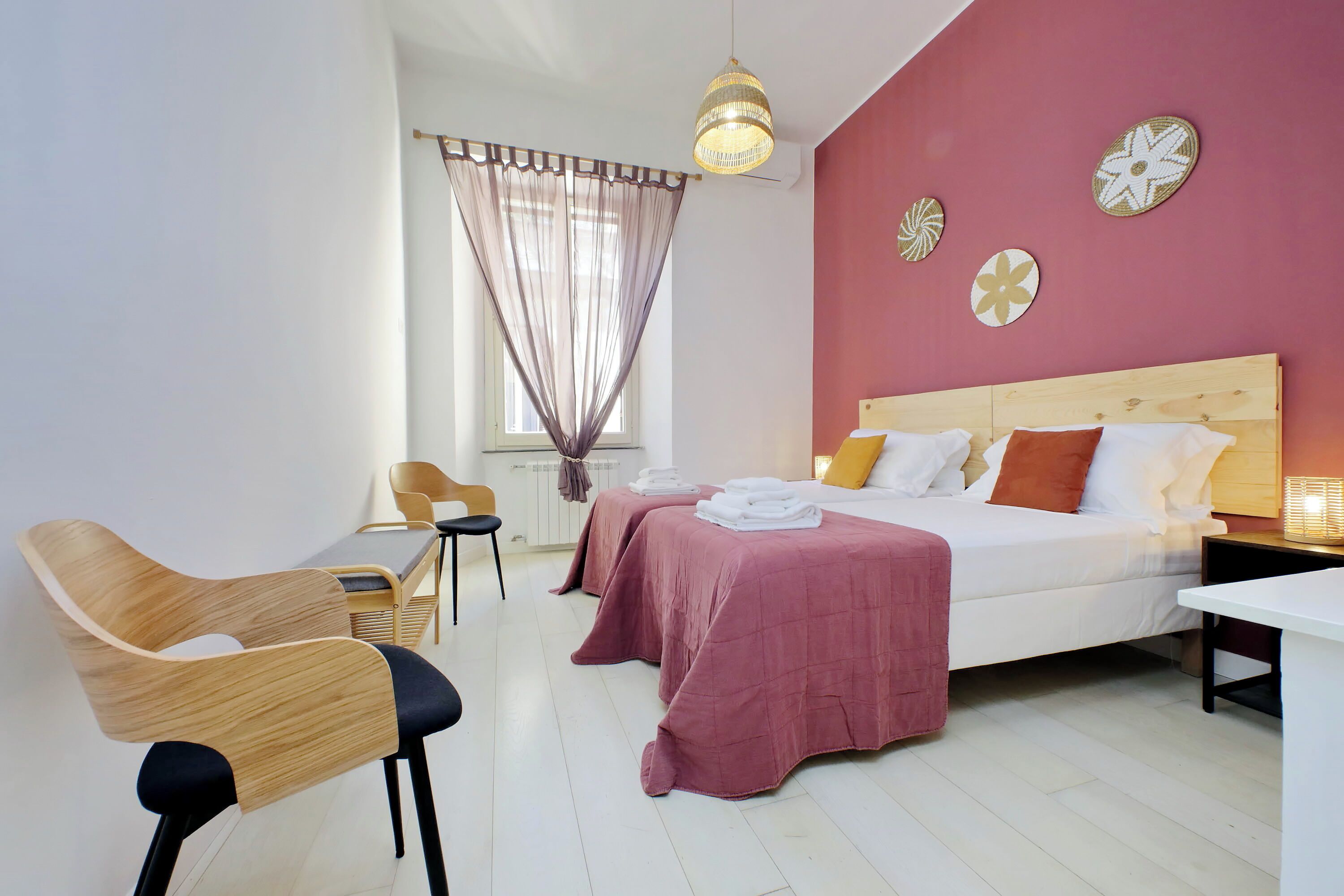A modern bedroom with a large bed, two bedside tables, a desk, and a chair.