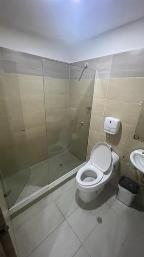 Un bagno con doccia vetro, water e lavandino.