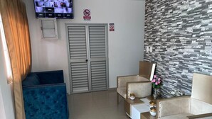 Una sala de estar moderna con un sofá azul, sillones color beige, una mesa de centro y un televisor montado en la pared.
