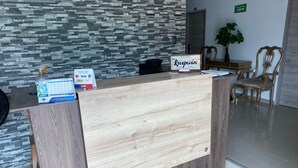 Un mostrador de recepción con detalles de madera, un cartel que dice "Recepción" y logotipos de Visa y Mastercard.