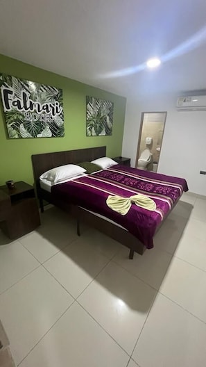 Una camera d'hotel con un letto, un comodino, una parete verde con un segnale e uno specchio.