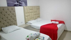 Habitación de hotel con dos camas, cada una con cabecera y ropa de cama blanca.