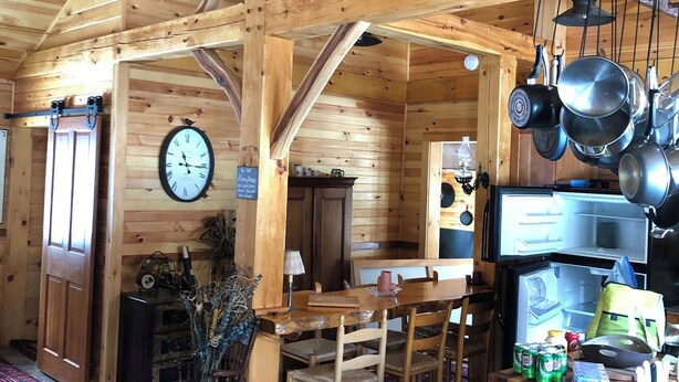 Un interior rústico de madera con comedor, refrigerador y un reloj en la pared.