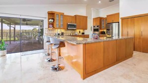 A modern kitchen with wooden cabinets, a granite countertop, and stainless steel appliances.