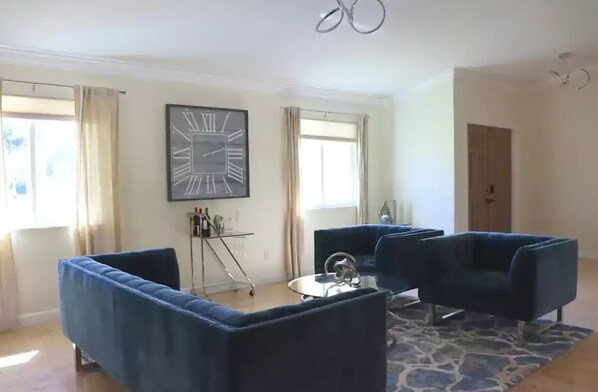 Un salón con dos sofás azules, una mesa de centro y un reloj de pared grande.
