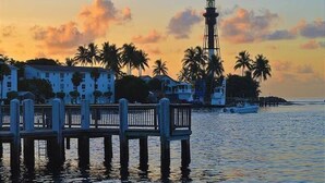 A waterfront property with a pier, a lighthouse, and palm trees. - Condo 300 steps from beach with heated pool and private free parking. (Pompano Beach)
