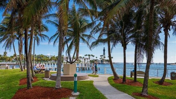 A waterfront park with palm trees, a pathway, and a view of the water. - Condo 300 steps from beach with heated pool and private free parking. (Pompano Beach)
