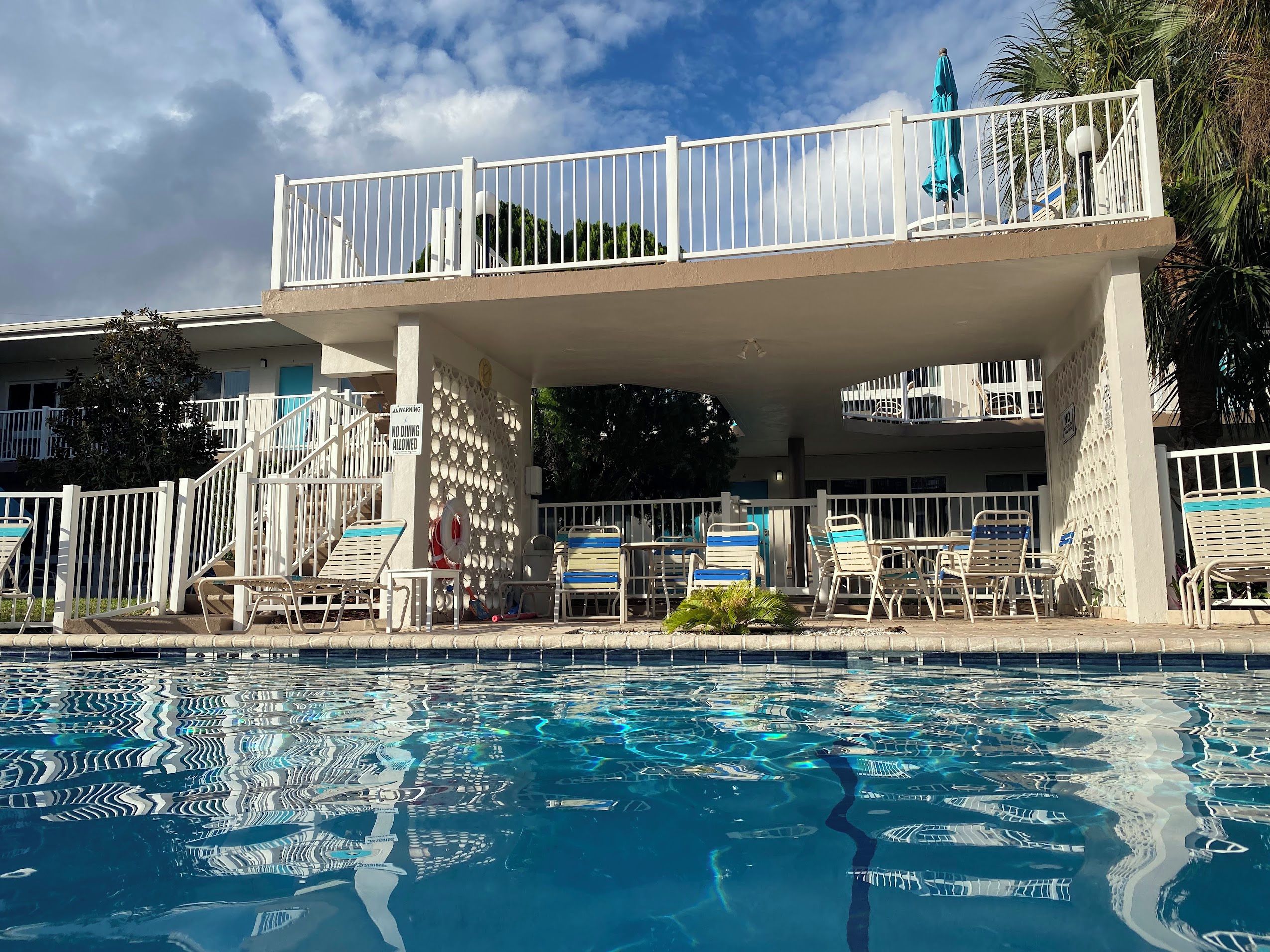 A swimming pool with a covered area, lounge chairs, and a no dining allowed sign.