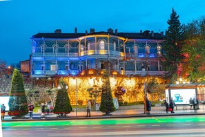 A historic building with a balcony, a stone facade, and a bus stop nearby. - Blue Balcony Hotel (Tbilisi)