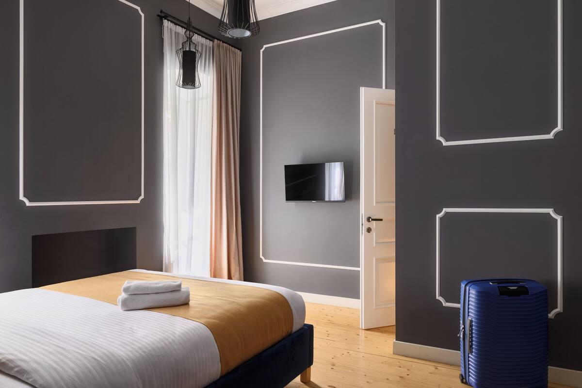 A modern hotel room with a bed, a television, and a suitcase.