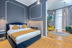 A modern bedroom with a large bed, bedside tables, and a seating area with a chair and sofa. - Blue Balcony Hotel (Tbilisi)