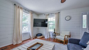 Ein Wohnzimmer mit großem Flachbildfernseher, einer Couch, einem Couchtisch und einem Sessel.