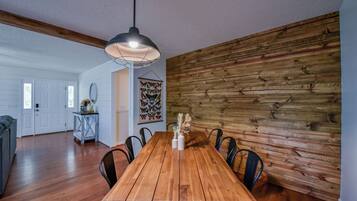 Un espace repas comprenant une table en bois, des chaises et un luminaire suspendu.