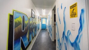 A hallway with graffiti on the walls and a caution sign warning of a slippery floor. - Furnished Glamping Tent/King Bed/Access to the Red River - Dancing Deer - #6 (Stanton)