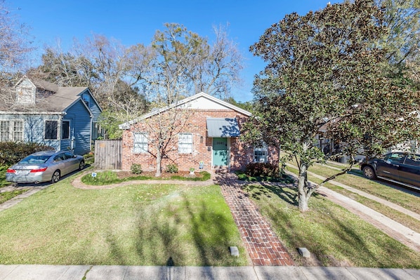 A residential house with a brick exterior, a front yard, and a driveway.