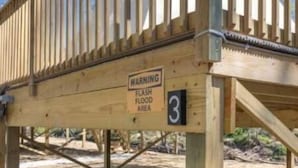 A wooden deck with a warning sign indicating a flood area.