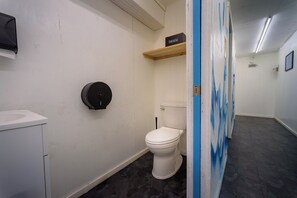 Et badeværelse med toilet, vask, en hylde med et skilt og en blå væg.
