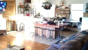 A spacious living room with a large brown leather sofa, a kitchen area with a bar counter, and a dining table. - Creeks Edge offers  full access to charming 8 acres along the river.
 (Canandaigua)