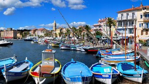 A marina with small boats docked, a church tower in the background, and buildings along the waterfront. - Air-conditioned studio with garden in Sanary Sur Mer (Sanary-sur-Mer)