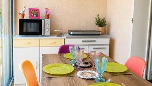A compact kitchen with a microwave, toaster, and small refrigerator. A dining table with colorful plates and glasses is set. - Air-conditioned studio with garden in Sanary Sur Mer (Sanary-sur-Mer)