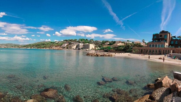 A coastal beach scene with clear water, rocky shoreline, and buildings in the background. - Air-conditioned studio with garden in Sanary Sur Mer (Sanary-sur-Mer)
